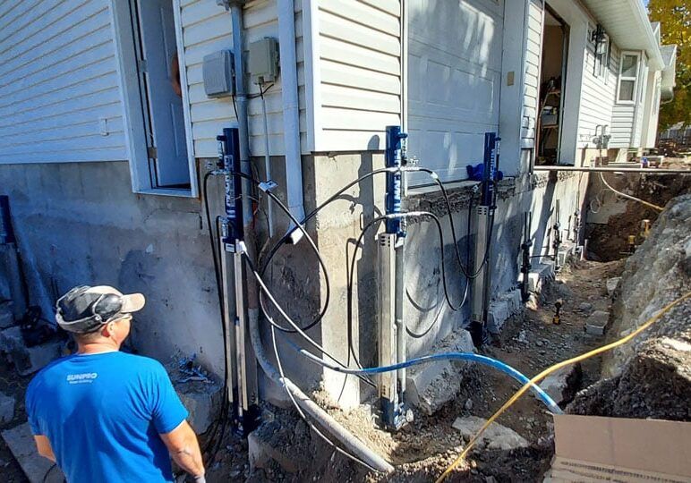 Hydraulic jacks lifting a settled house foundation on a Poly-Lift job