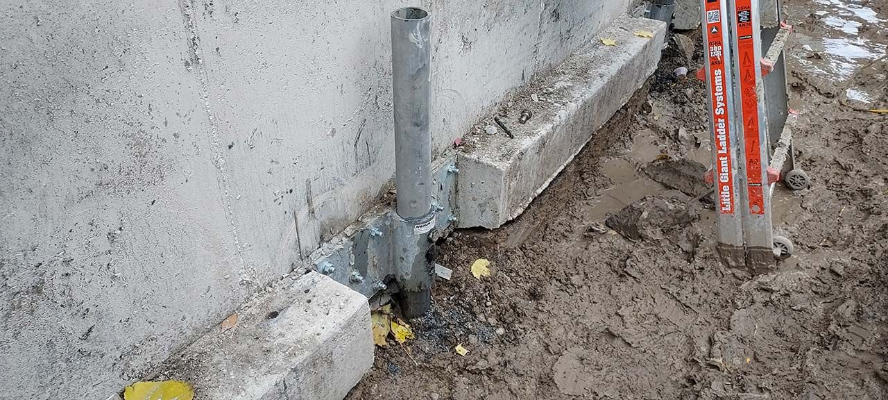 Galvanized push-pier bracket fastened to a foundation wall
